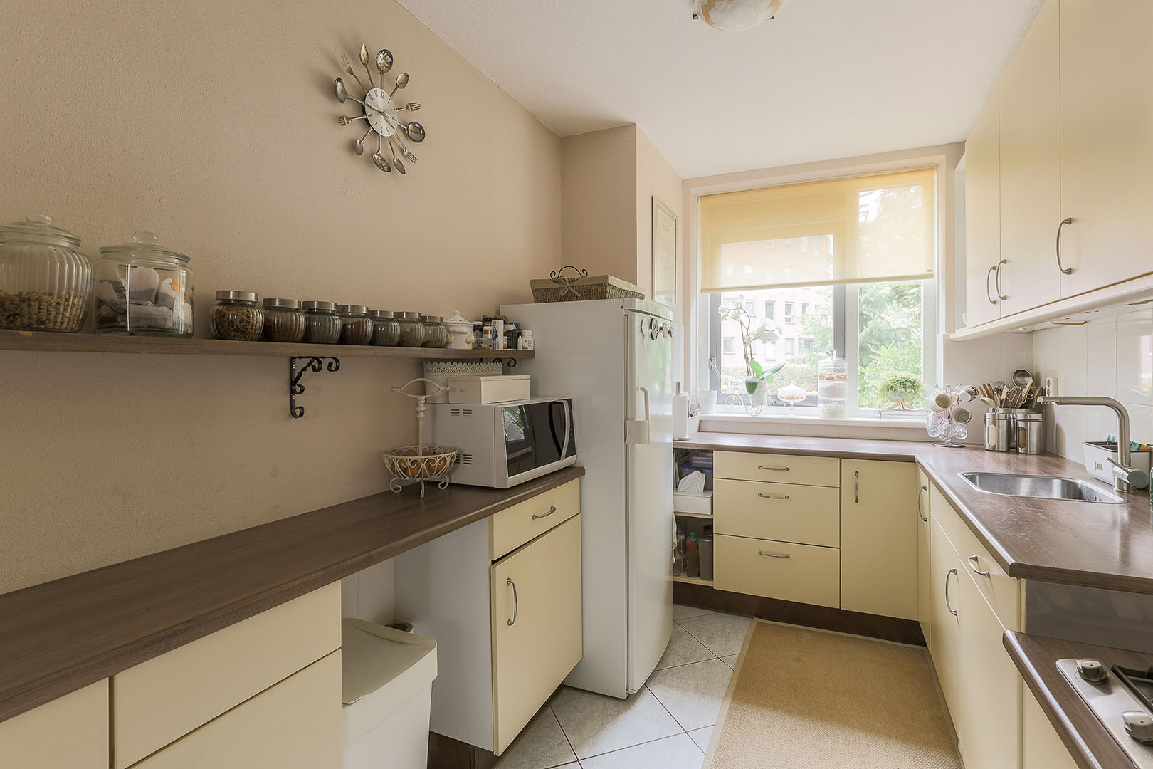Table with chairs and flowers located near lounge area and kitchen in spacious room of contemporary apartment
